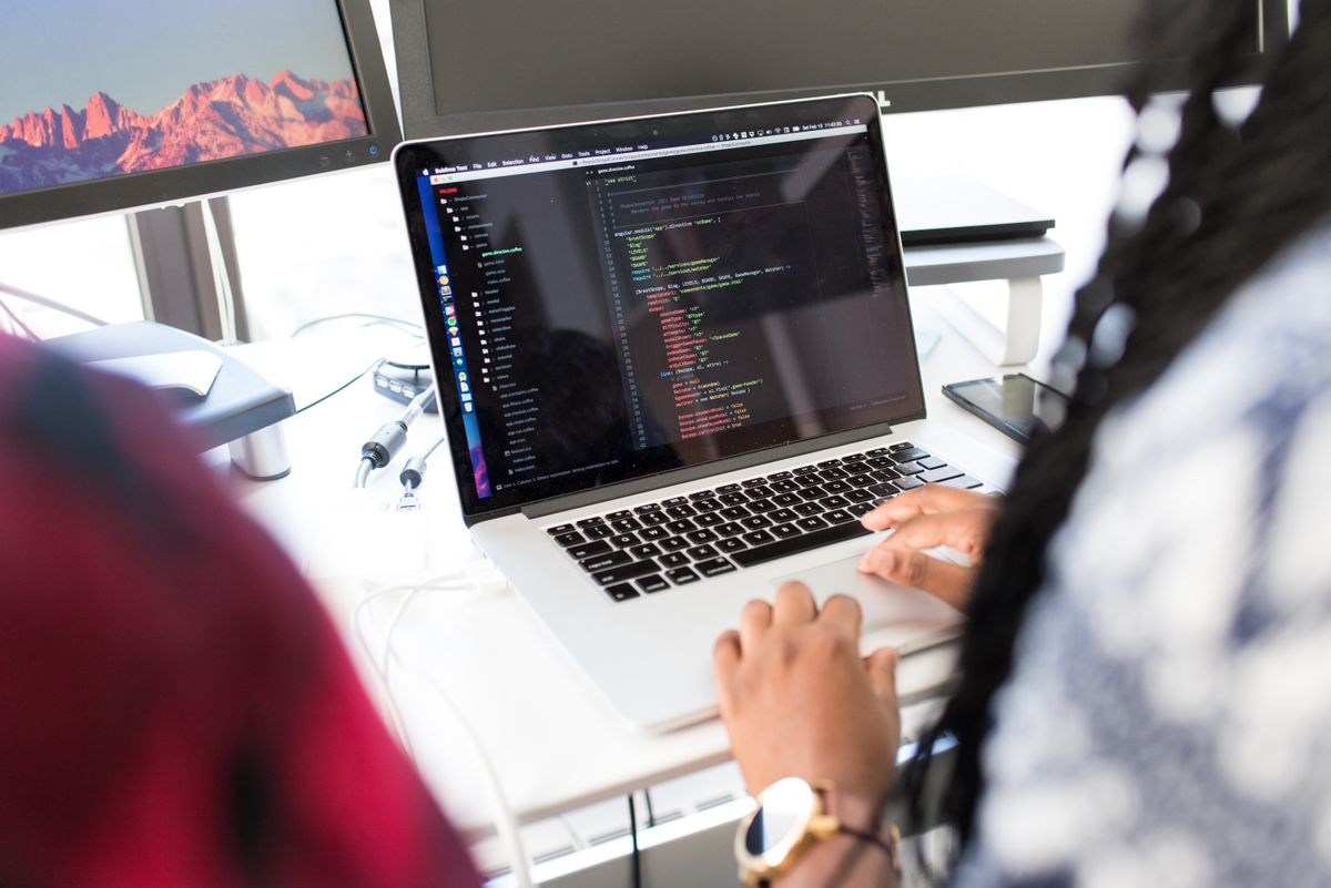 Application code open on a laptop beside a second monitor